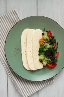 Sliced Imeruli cheese, Georgian cheese, with vegetables, top view, no people