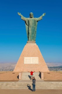 Tourists taking photos in front of the large statue of Christ on the Morro de Arica lookout