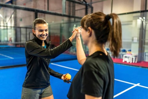 Female athletes sharing a supportive high five gesture after playing a pickleball match on an
