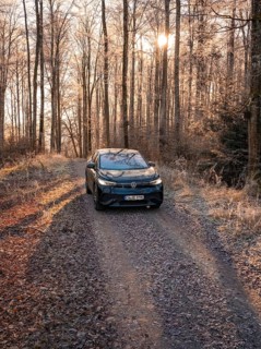 A car on a forest path at sunrise, surrounded by frosty grass, car sharing, electric car,