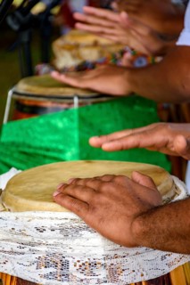 Several atabaque drums decorated with fabric being used during an Umbanda religious ceremony in