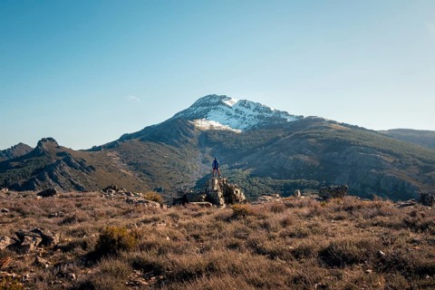 Back view of an unrecognizable person standing on a rock at the summit of Mount Ocejon, in