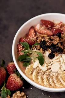 A breakfast natural bowl featuring fresh strawberries, bananas, nuts, and granola, sprinkled with