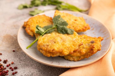 Fried crispy Chicken pancakes on brown concrete background and orange linen textile. side view,