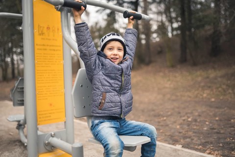 Young boy smiling and exercise at the outdoor gym in Wroclaw, Poland