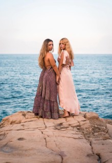 A couple of Caucasian girls in beautiful dresses enjoying the summer, shaking hands in an