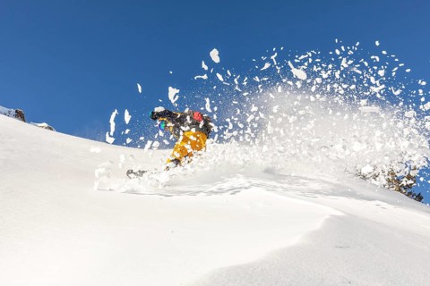 Snowboarder expertly carves through fresh powder on a sunny winter day, showcasing the thrill of