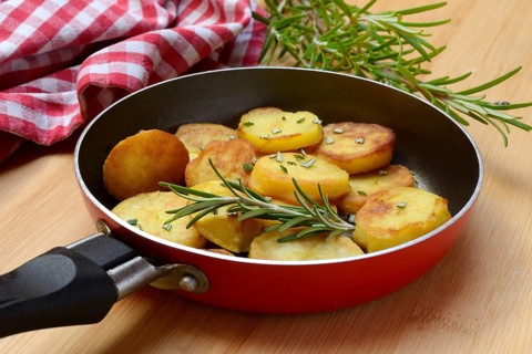Fried potatoes in pan with rosemary sprig