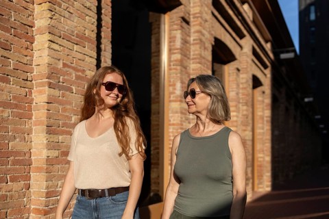Mother and daughter walk together, enjoying a sunny day while sharing smiles and good company. The
