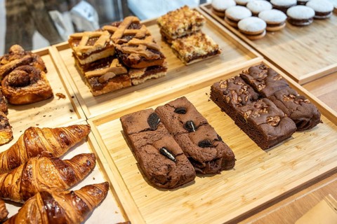 Various baked goods including croissants, tarts, and brownies arranged on wooden trays, showcasing