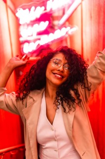 Vertical portrait of a happy beautiful latin woman with chic clothes and curly hair dancing next to