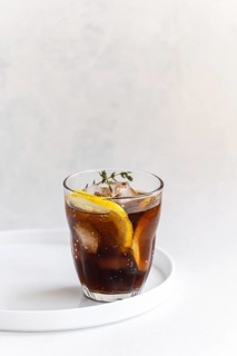 A refreshing gin cocktail presented in a clear glass with cola drink, garnished with fresh thyme