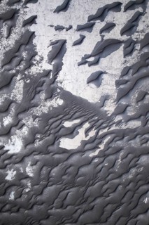 Close-up image capturing the intricate textures of black sand alongside peeling white paint,