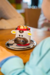 Child enjoying dessert in a funny cow cup with cream and cherries, autumn creations, Cafe Kuh,