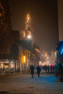 Evening street scene with illuminated church tower, pedestrians and Christmas atmosphere, Christmas