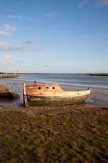 Abandoned old wooden boat rotting on the shoreline on the River Ore at Orford, Suffolk, England,