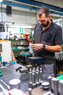 Man using micrometer analyzing the quality and measure of metal pieces