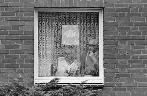A retired couple looks out the window of their apartment at the passing Ruhr Easter March 1983.