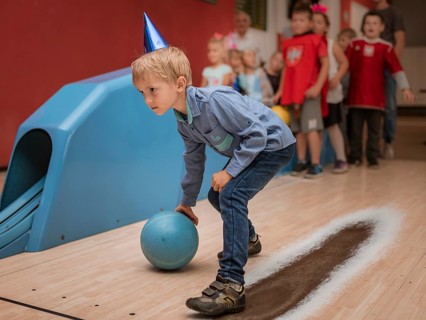 Six years old boy playing bowling during birthday party