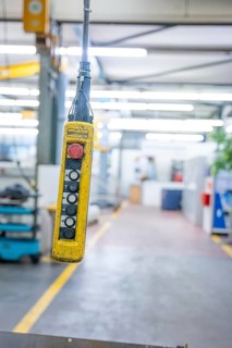 Yellow remote control for hoists in industrial environments with bright lighting