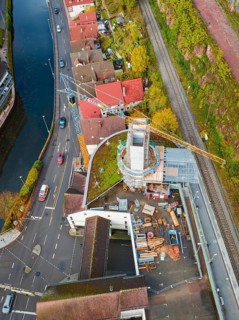 Aerial view of a construction site with construction crane and surrounding roads and river,