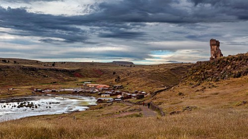 Hilly landscape with clouds and a small settlement in the distance, The Chullpas of Sillustani near