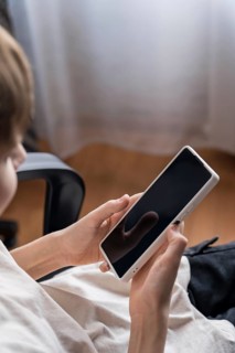 A teenager engrossed in his smartphone, presumably preparing to play. The scene captures youthful