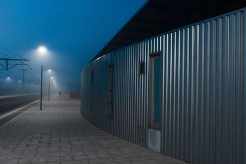 A mysterious atmosphere envelops a solitary figure strolling down a fog-covered railway station