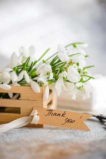Spring snowdrops freshly gathered in a wooden crate, accentuated by a rustic Thank you! tag,
