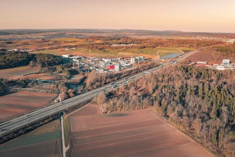 Industrial area on a motorway line, surrounded by fields and forests at sunset, A8 near Wurmberg,