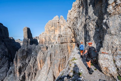 Three mountaineers on an exposed rock band in the secured Via Ferrata Bocciere Centrale via