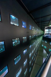 Dark, modern showroom with numerous illuminated screens on the walls, Deutsche Kinematik, Berlin,