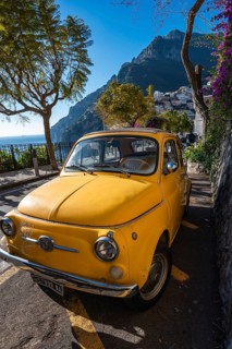 POSITANO, ITALY - JANUARY 13, 2024: Amalfi Coast in Positano, Italy. Beautiful old yellow car Fiat
