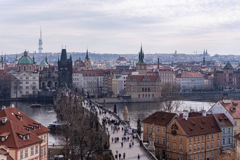 Overlooking Prague's historic skyline featuring Charles Bridge bustling with tourists, with the