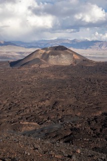 A volcano in a dry desert landscape under a cloudy sky, Argentina, volcanoes, lava field,