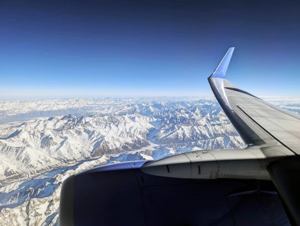 Aerial view of snow-capped mountains seen through an airplane window, showcasing a stunning
