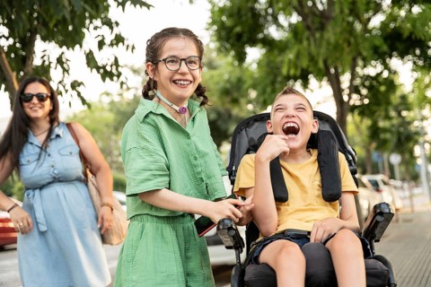 A joyful family outing shows a girl with a tracheostomy and a boy with cerebral palsy in a