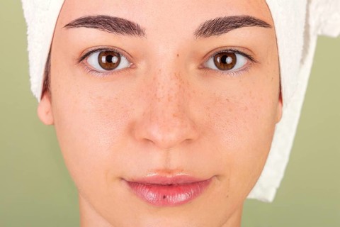 Close-up of a woman's clean, fresh face wrapped with a towel, representing beauty, self-care, and