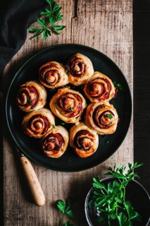 Delicious chorizo bread rolls beautifully arranged on a dark plate, set on a rustic wooden table.