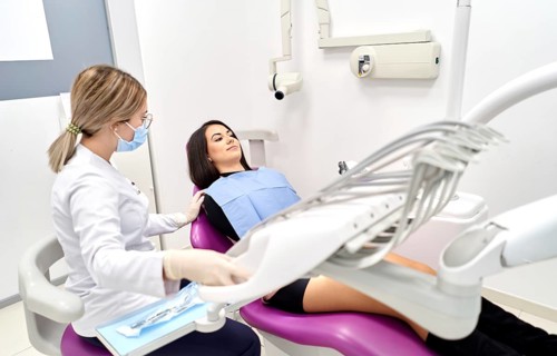 A patient relaxes in a modern dental clinic while a hygienist prepares for a check-up. The clinic