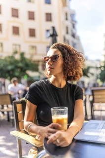 Vertical photo of a beauty arab woman drinking coffee in an outdoor cafeteria in a sunny day of
