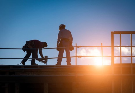 Construction Workers Silhouette on Roof of Building