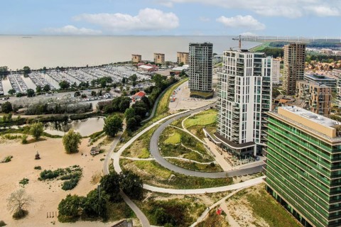 A scenic view showcasing modern buildings alongside a marina. The natural landscape merges with
