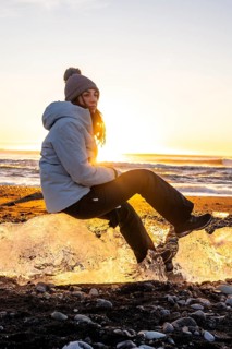 Portrait of woman sitting on a piece of ice at sunset on Diamond Beach in Iceland