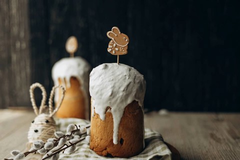 Traditional Russian kulich bread topped with white glaze and cute Easter-themed decorations,