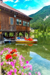 Colorful pedal boats dock under a traditional wooden boathouse on the clear waters of lake