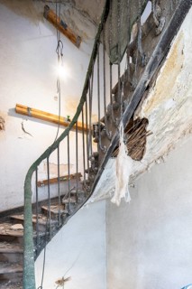 A damaged staircase in an old building undergoing renovation. Exposed areas show deterioration,