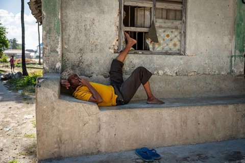 PAJE, ZANZIBAR - OCTOBER 18, 2025: A local man relaxing on a stone bench outside a traditional