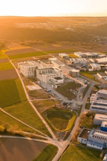 Area with new buildings and green fields in a growing region, captured from the air at sunset, new