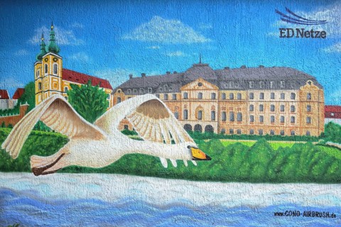 Mural with castle, St. Johann church and humped swan flying over Danube, street art, graffiti, swan